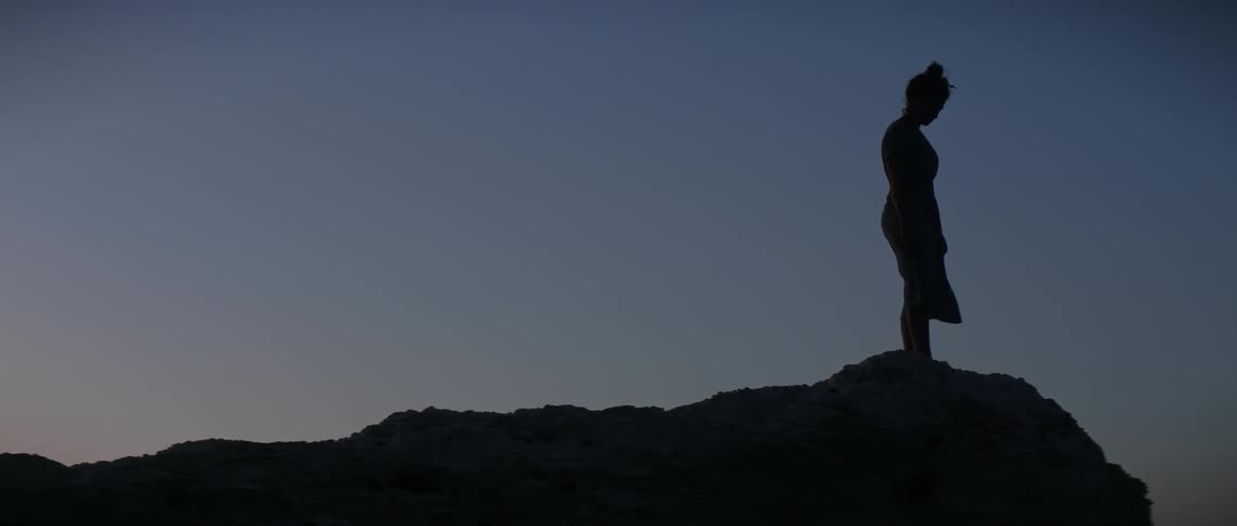 Woman walks on hilly landscape in the evening