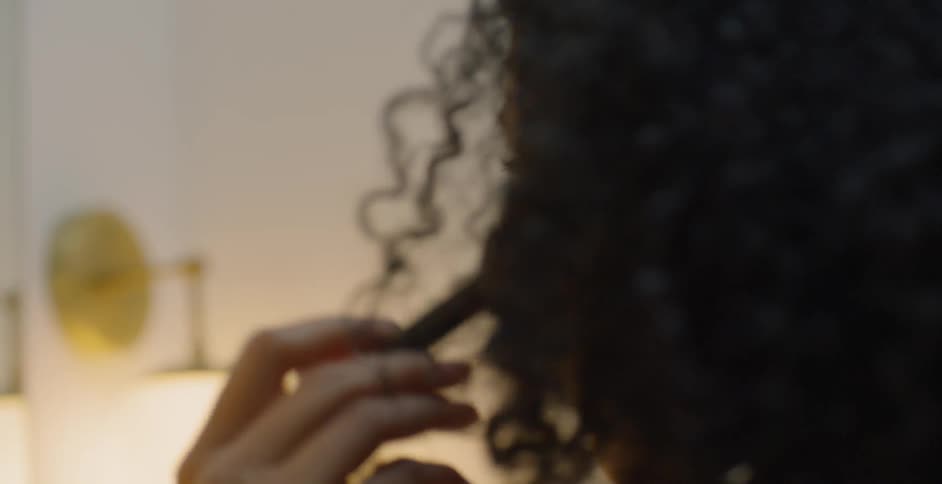 The woman uses a brush on her face looking in the mirror