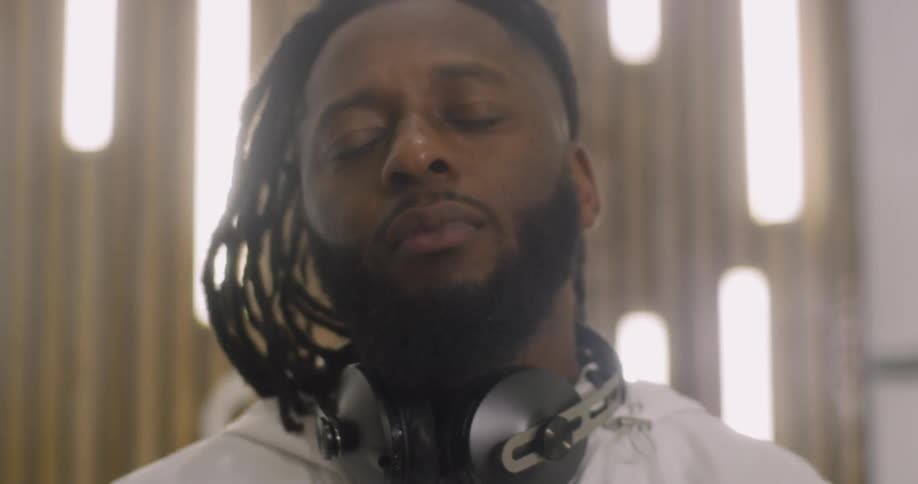 Man with headphones around his neck blinks his eyes and licks his lips