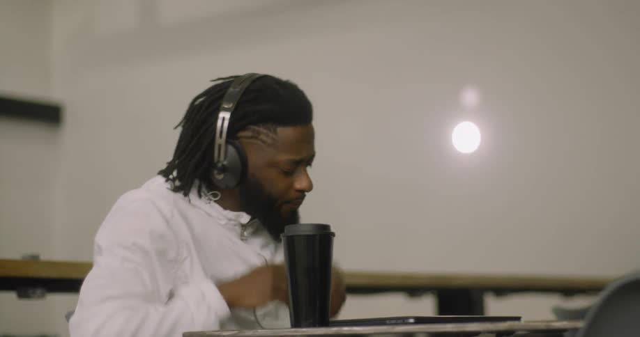 The man sits down with his laptop and drink