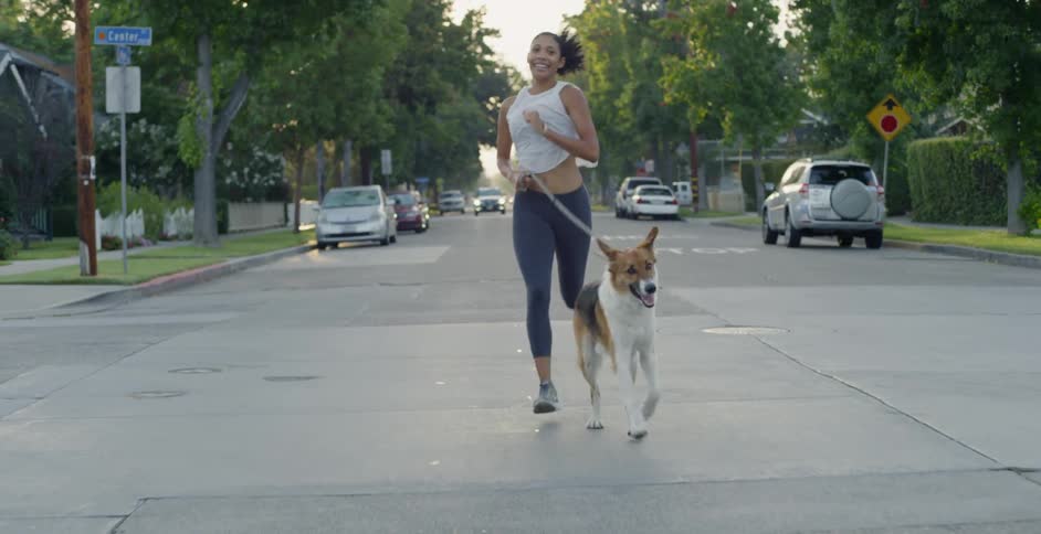 Woman jogs with her dog down a city street
