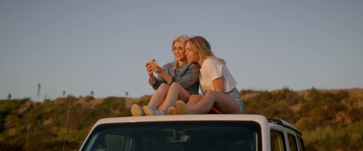 Two women pose for a picture that one woman takes with her camera