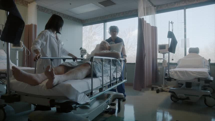 Nurse and doctor pushing a man on a gurney towards a window