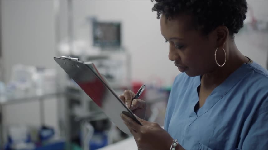 A woman smiles as she writes on a clipboard