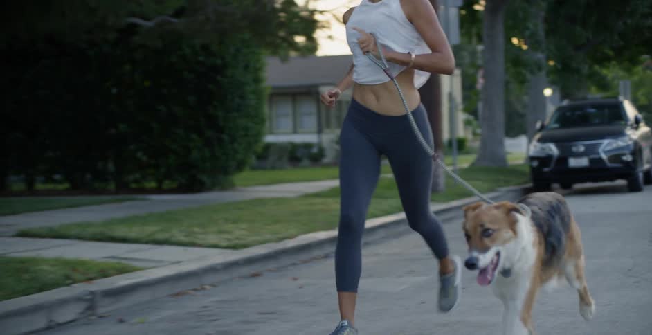 Woman jogs with her dog down a city street