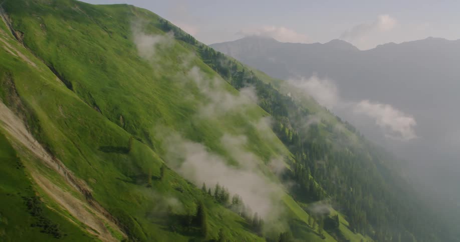 The fog rolls over the green mountain
