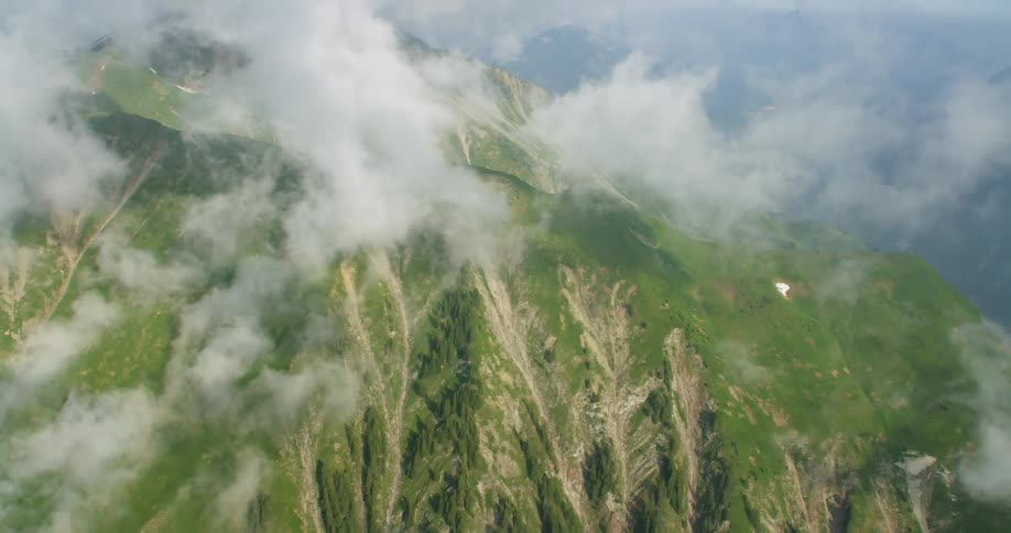 The green mountains have clouds rolling overhead