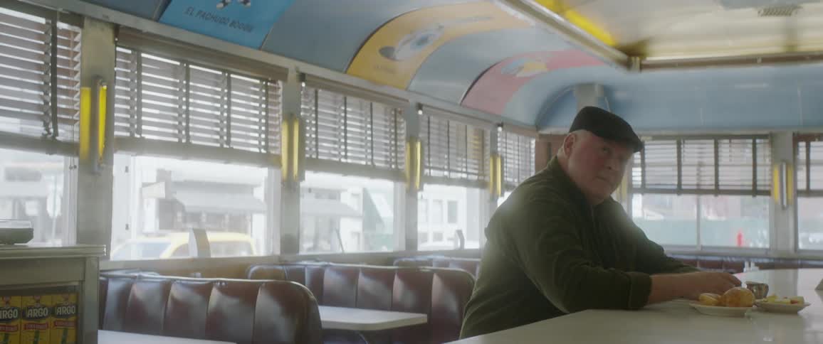 An elderly man eats at a counter in a diner
