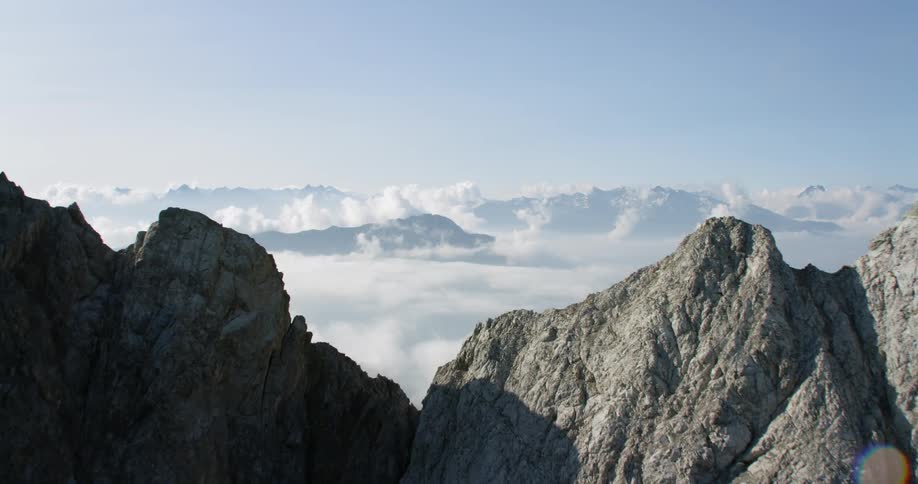 The tall grey mountain leads to cloud covered mountains behind it