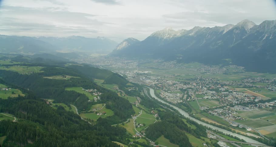 A river is flowing past a village in a mountain valley on a cloudy day