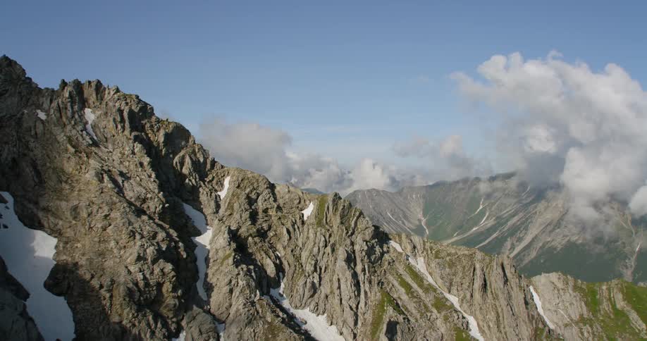 Clouds hover on top of rocky mountains
