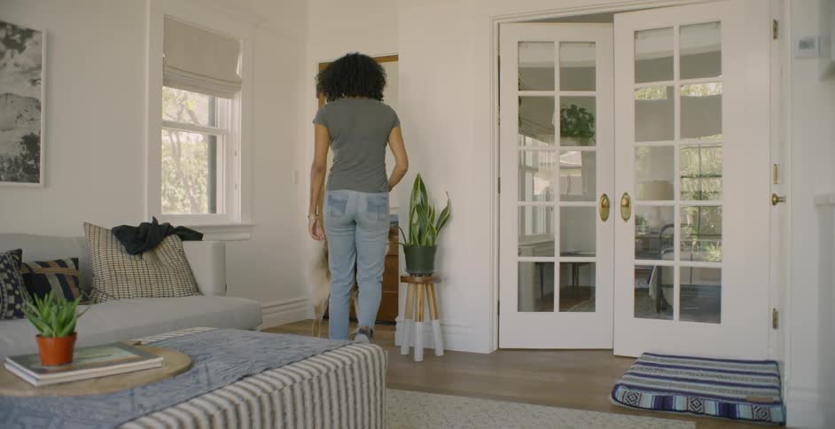 Woman and dog greet a person at the door