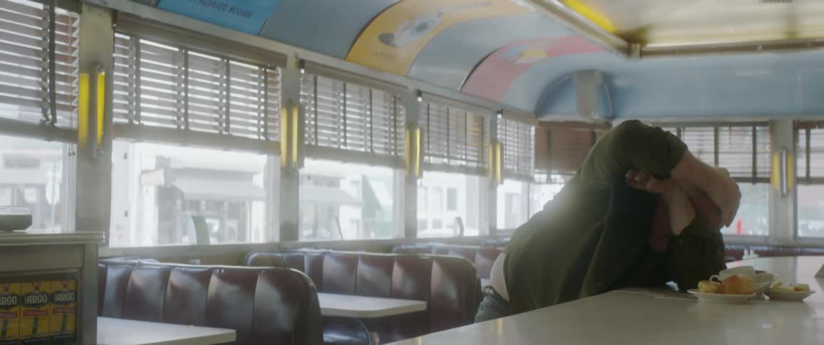 The man cowers in the diner as he is being attacked