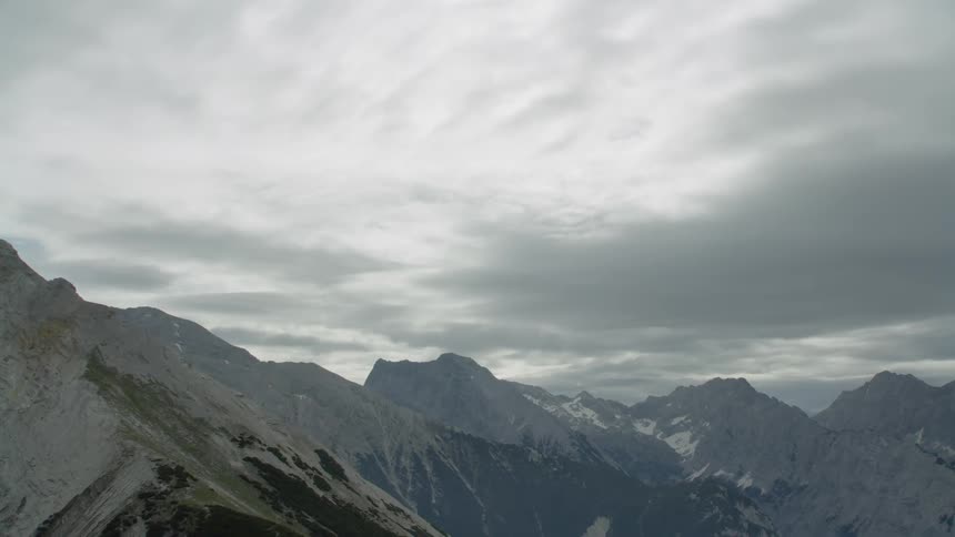 Sun shines slightly through clouds over mountains