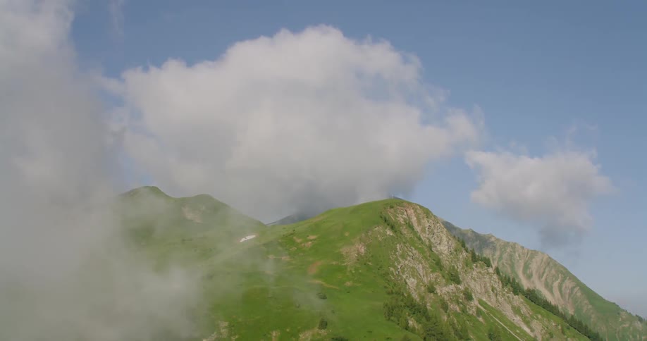 Clouds hover low over a grassy mountain top