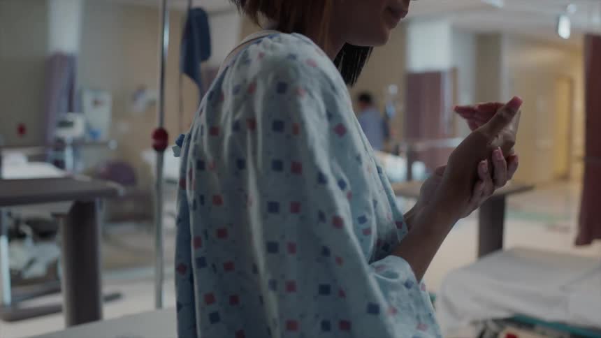 A patient in a hospital rubbing her hands together