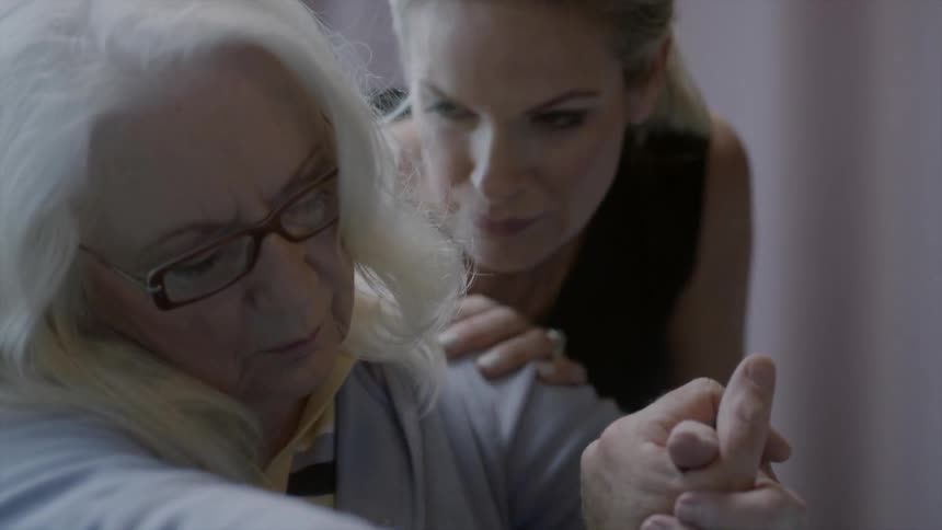 Younger lady comforting an older woman sitting up resting