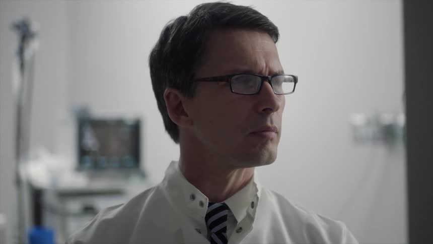 A man wearing a tie and glasses reading something then making a note