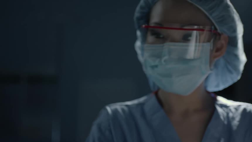 A doctor looks over a patient that is laying in a hospital bed