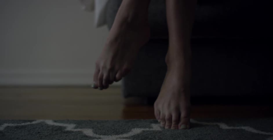 A woman's feet dangling with only one on the floor
