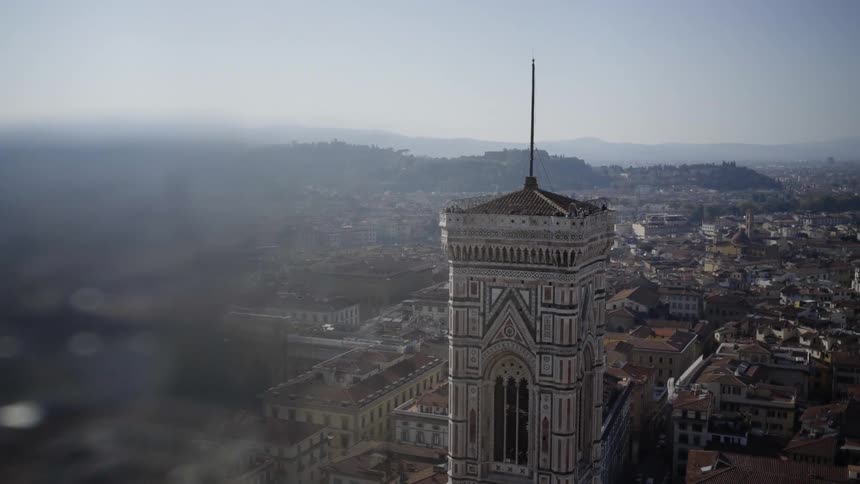 View of an old city with hills in the background and a tower in foreground