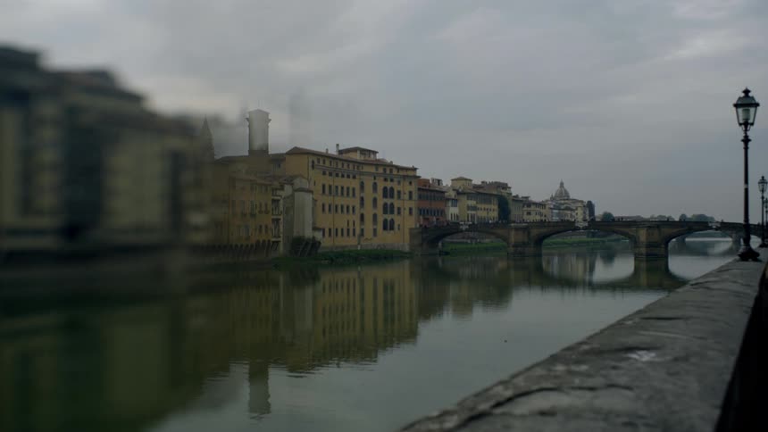 A view of a river and bridge next to buildings on a cloudy day