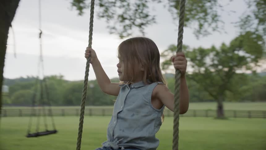 Man pushes a small child on a swing