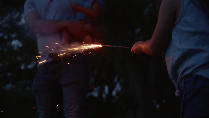 Little girl holds a sparkler as a man lights it for her