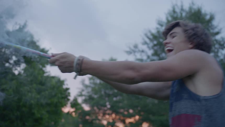 Man holds a long piece of fireworks as flames shoot out of it