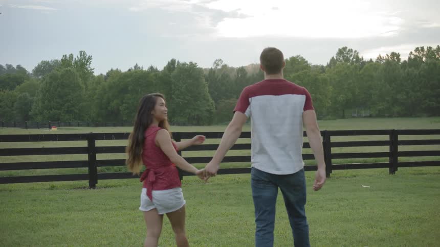 A man and woman hold hands on a farm