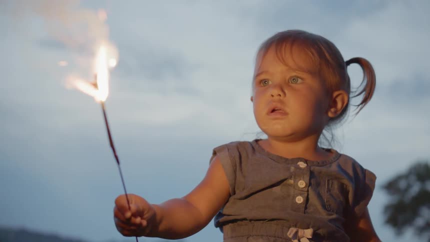Little girl holds a flaming sparkler