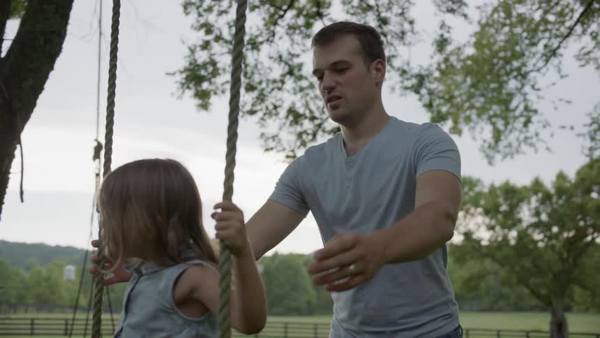 Father pushes young girl on swing