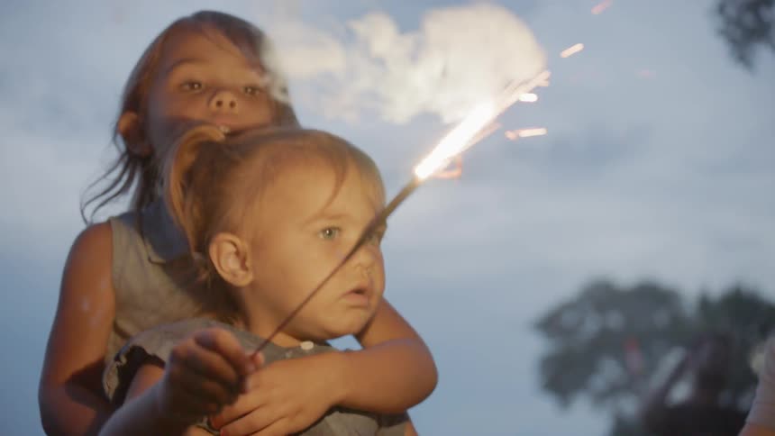 The children play with sparklers on the field at sunset