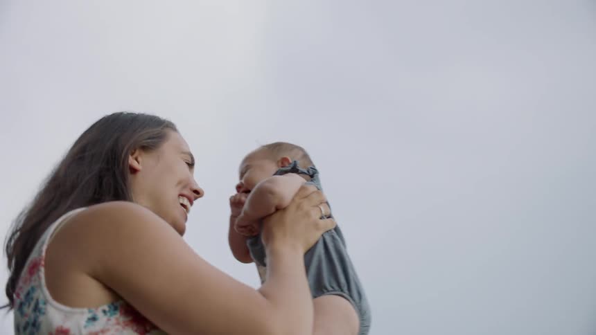 Woman raises a baby in the air smiling