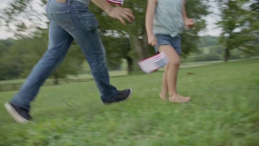 A father is chasing his daughters outside in a rural setting as his wife watches