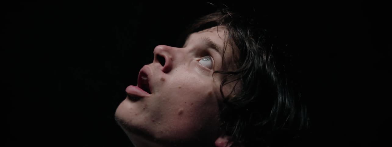 Man stands in a dark room looking up in surprise