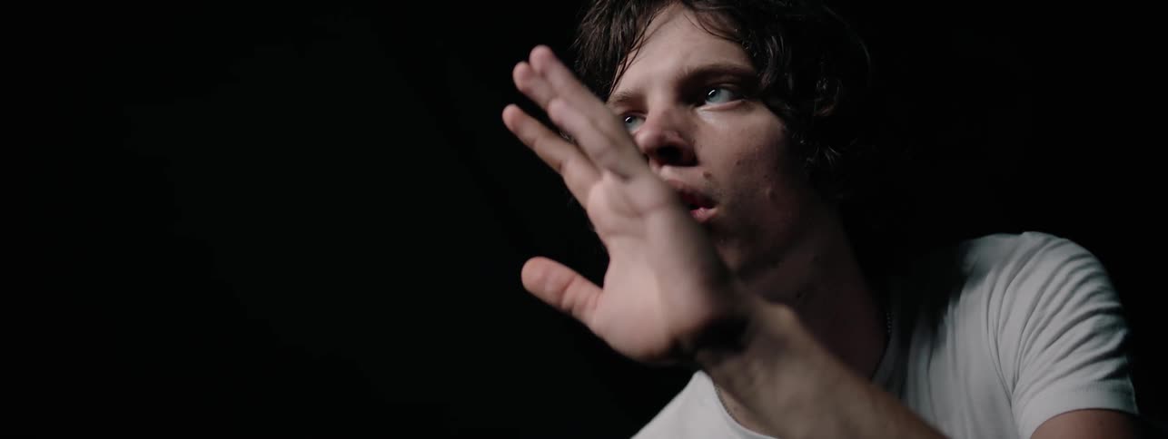 A boy holds up his hand and turns it in front of his face as he stares at it