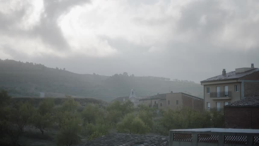 Clouds float above houses on a hill