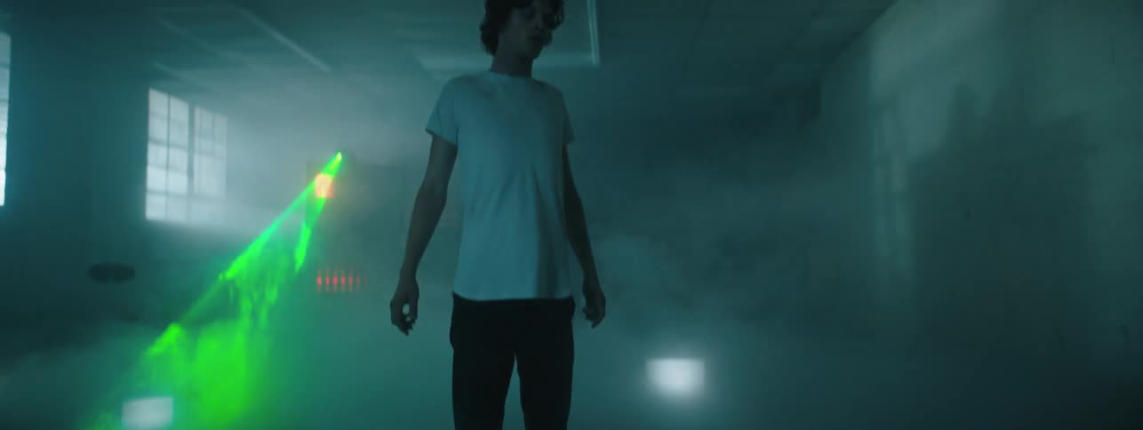 Man walks through the mist in the room as a green light shines back and forth