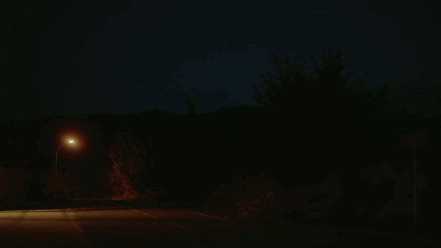A street lamp on a rural road glows at night