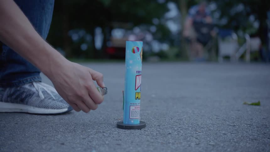 The person lights a firework on the ground and backs up