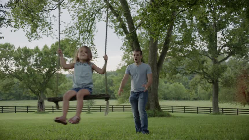 Man pushes a child on a swing