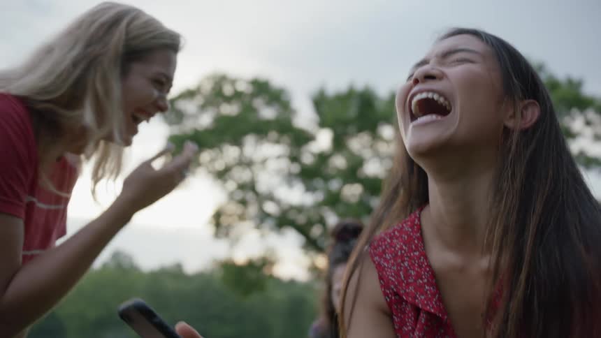 The women laugh together checking the phone