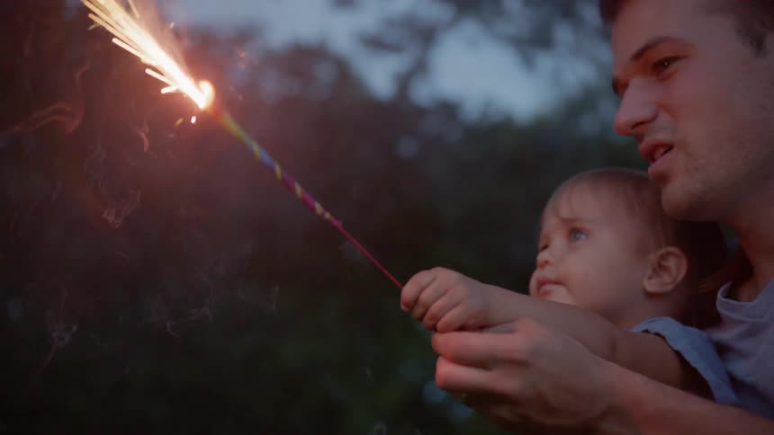 The man raises a sparkler with a child