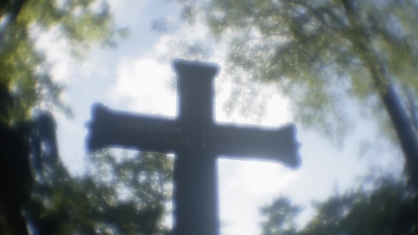 The cross is in the cemetery on a cloudy day