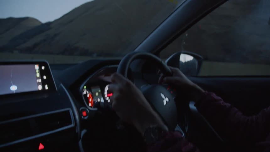 The man is driving a vehicle at sunset