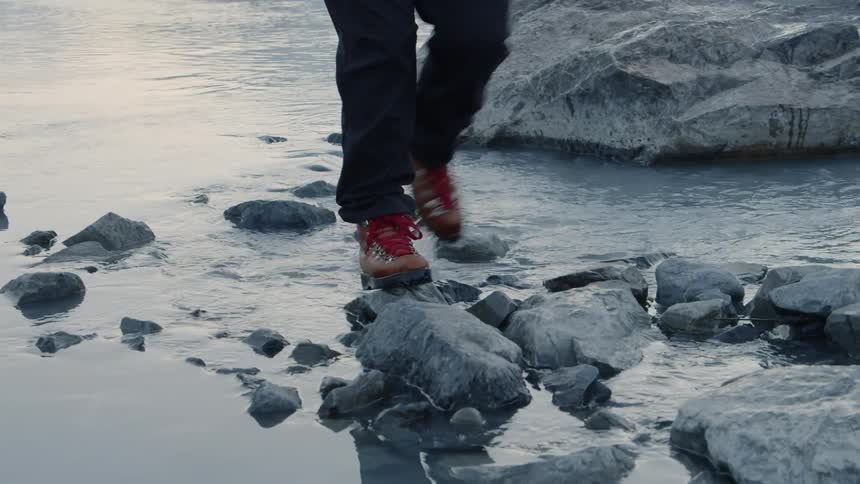 Someone walks on rocks in a river on a bright day