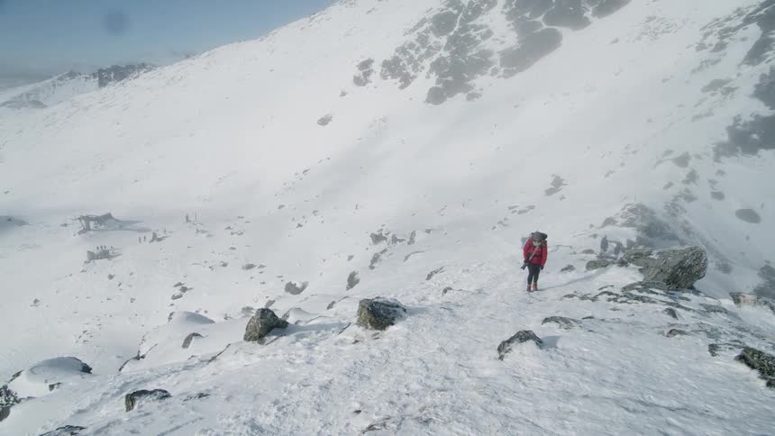 A woman hikes up the snowy mountain