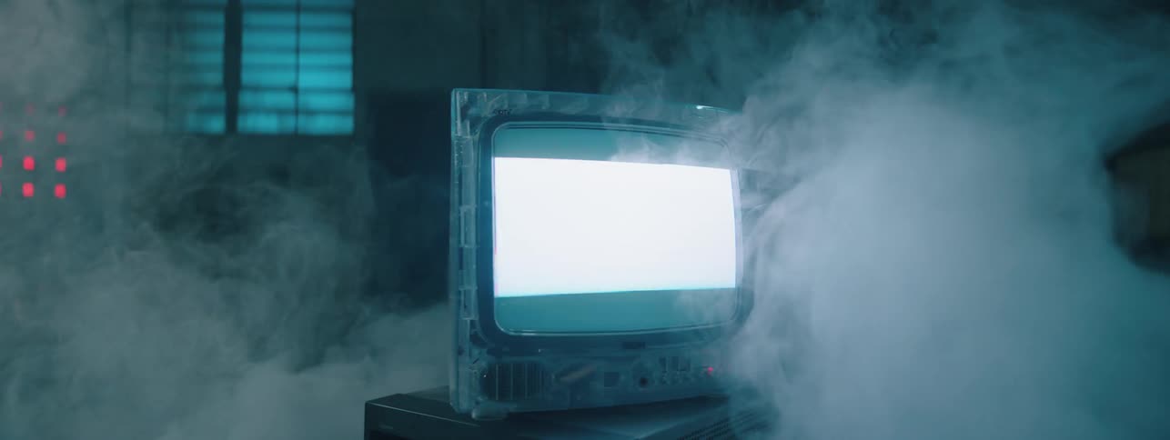 A computer monitor is flickering as smoke swirls around it inside a room