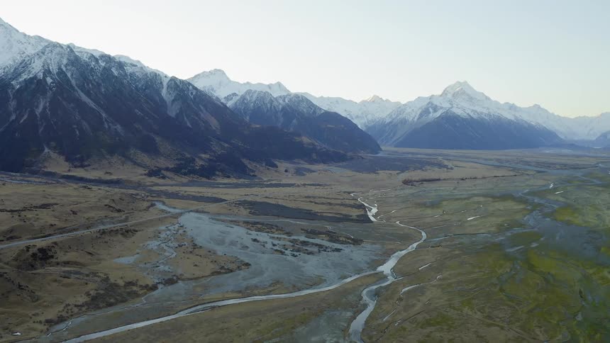 A stream of water winds through the flat lands from the mountains